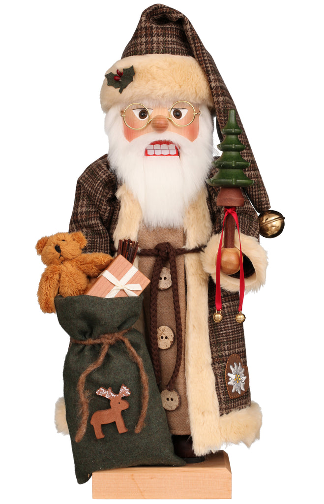 The Christian Ulbricht Collectible Wooden Nutcracker - Santa Claus in Brown Checkered Coat is a festive German nutcracker dressed as Santa, featuring a brown plaid coat and hat. It holds a small tree and a green sack with a reindeer design, and the limited-edition piece includes a teddy bear and a gift inside. The nutcracker is complete with white hair, a beard, and glasses.