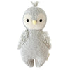 A hand-knit Cuddle + Kind Baby Penguin with a tuft on its head, wing details, and yellow beak, crafted from Peruvian cotton yarn, isolated on a white background.