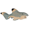 A wooden toy shark painted in shades of blue and light tan with black-tipped fins. The handcrafted wood shark has a simplistic, hand-carved appearance with minimal facial features, including a small eye and an open mouth, reminiscent of Holztiger Shark figures.