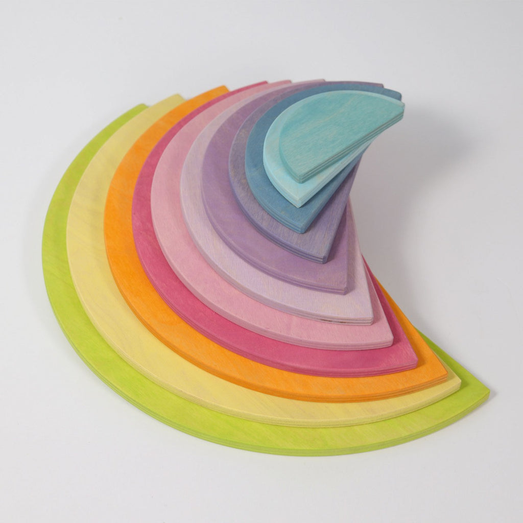 A set of Pastel Semi Circle Set painted in rainbow colors are neatly stacked on top of each other, ranging from green at the bottom to blue at the top. The semicircles gradually decrease in size, forming an ascending spiral shape reminiscent of modern architecture and perfect for an extra-large creative puzzle.