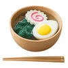 A wooden bowl filled with toy food resembling ramen ingredients, including a spiral fish cake, a leaf, and a sunny-side-up egg made from natural non-toxic materials. Wooden chopsticks are placed below the bowl, making it an ideal Ramen Bowl Playset (ships in approximately one week) for sensory play food activities.