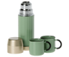 A Maileg | Miniature Thermos And Cups with its cap off and two matching green cups, one with a black handle, arranged on a white background.