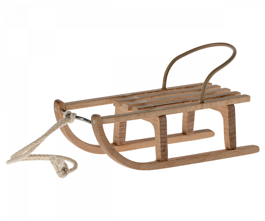 A small Maileg Christmas Mini Sled with a simple design, featuring metal supports and a sturdy rope for pulling. This classic winter accessory boasts slatted seating and curved runners, ideal for gliding over snow. A perfect snow toy for all ages to enjoy the frosty outdoors.