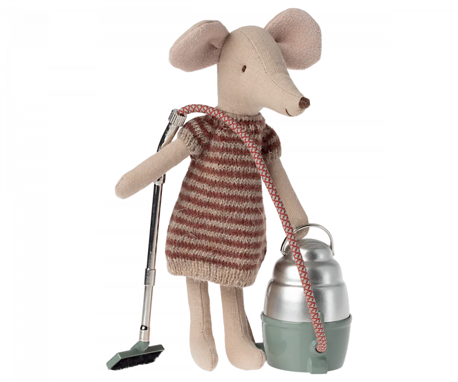 A plush mouse toy dressed in a striped sweater, holding a Maileg Miniature Vacuum Cleaner and carrying a green metal lunch box with a red strap, isolated on a black background. This Maileg Mini Hoover accessory adds