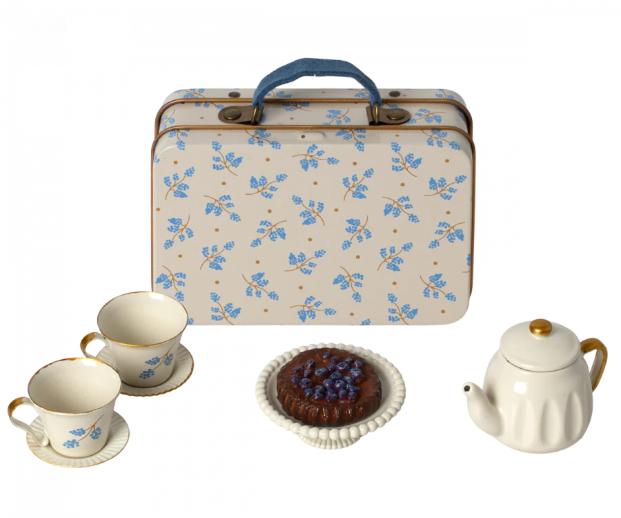 A vintage floral metal suitcase with a Maileg Miniature Afternoon Treat Tea Set - Blue Madelaine, depicting a quaint tea setting.