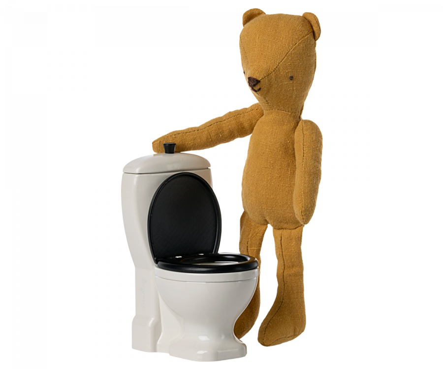 A brown teddy bear stands next to the Maileg Miniature Toilet - Teddy Size, appearing as part of a cute bathroom assortment. The bear's right paw rests on the toilet tank, set against a white background, giving full focus to this charming teddy family scene.