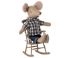 A small, light brown Maileg Rocking Chair, Mouse - Light brown sits in a miniature wooden rocking chair. The mouse, part of a charming mouse family, is dressed in a blue and white plaid shirt and blue jeans, with its legs stretched out and arms resting on the chair's arms.