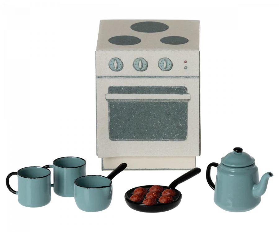 A Maileg Madam Blue’s Favorites, featuring a mini stove, three blue cups, a blue teapot, and a frying pan with four meatballs. The stove has four burners with three control knobs and an oven door. All items are styled in muted colors, predominantly blue and gray.