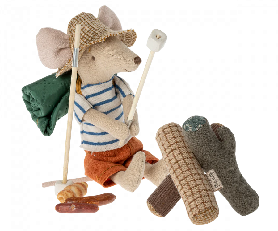 A whimsical Maileg Hiker Mouse dressed as a hiker with a striped shirt, shorts, and hat, equipped with a walking stick and a green backpack, standing next to the Maileg Campfire.