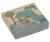 Illustrated cardboard box depicting a cozy camping scene with anthropomorphic mice, featuring a Maileg Happy Camper Tent, campfire, and river. The box is labeled "Happy Camper.