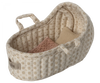 A small, beige, fabric Maileg Carry Cot, Micro with a quilted pattern and floral designs. The cot contains two small pillows, one pink and the other light beige. This versatile piece doubles as a micro-sized bunny bed or portable rabbit carrycot, complete with soft handles for easy carrying.