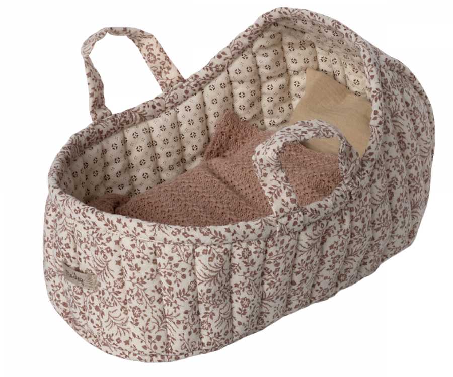 Introducing the Maileg Carry Cot, Large - Off White: A soft fabric carrycot adorned with a quilted floral pattern in soothing shades of brown. It features two convenient handles and offers a cozy interior, complete with a warm knitted blanket and a beige pillow, creating the ideal portable bed for your little one.