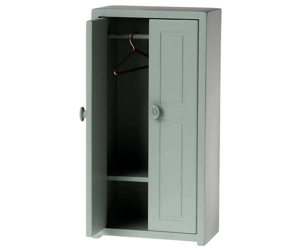 The Maileg Mouse Closet in Soft Blue presents a simplistic charm with its one partially open door, inside which an empty hanging rod holds a single golden hanger and a shelf. Sitting against a plain backdrop, the closet's minimalistic design invites you to imagine perhaps even a little mouse family taking residence within. Shipped approximately one week after order placement, this product combines function with whimsy.