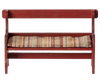 The Maileg Mouse Bench - Red, available in approximately one week, is a compact wooden piece with a vintage aesthetic, featuring a red finish and a woven seat cushion with multicolored stripes. Its straightforward design includes both backrest and armrests, ideal for adding nostalgic charm to any room.