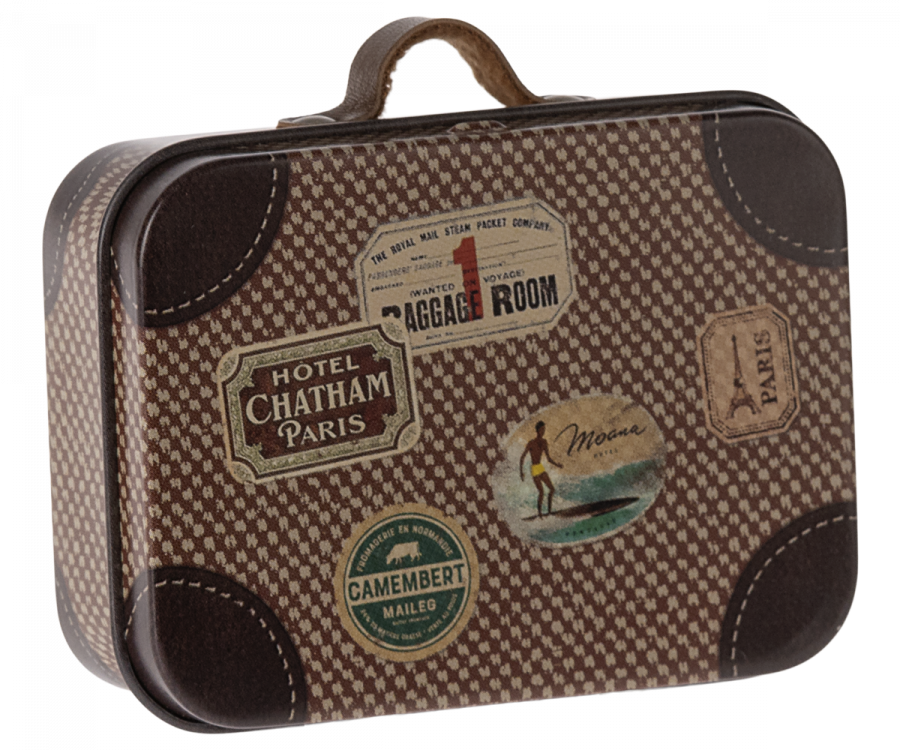 The Maileg Suitcase, Micro is a small metal suitcase with a brown vintage-style design featuring a checkered pattern and colorful travel sticker illustrations, including ones for Hotel Chatham Paris, Camembert, and a surfer labeled "Mona." Ideal for storing small items, it also includes a handle at the top.