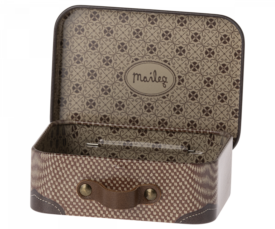 The image displays the Maileg Suitcase, Micro, a small vintage-style metal suitcase perfect for storing small items. The interior is adorned with a brown and beige floral pattern, while the exterior features a houndstooth design complemented by brown leather accents and a handle secured with brass rivets.