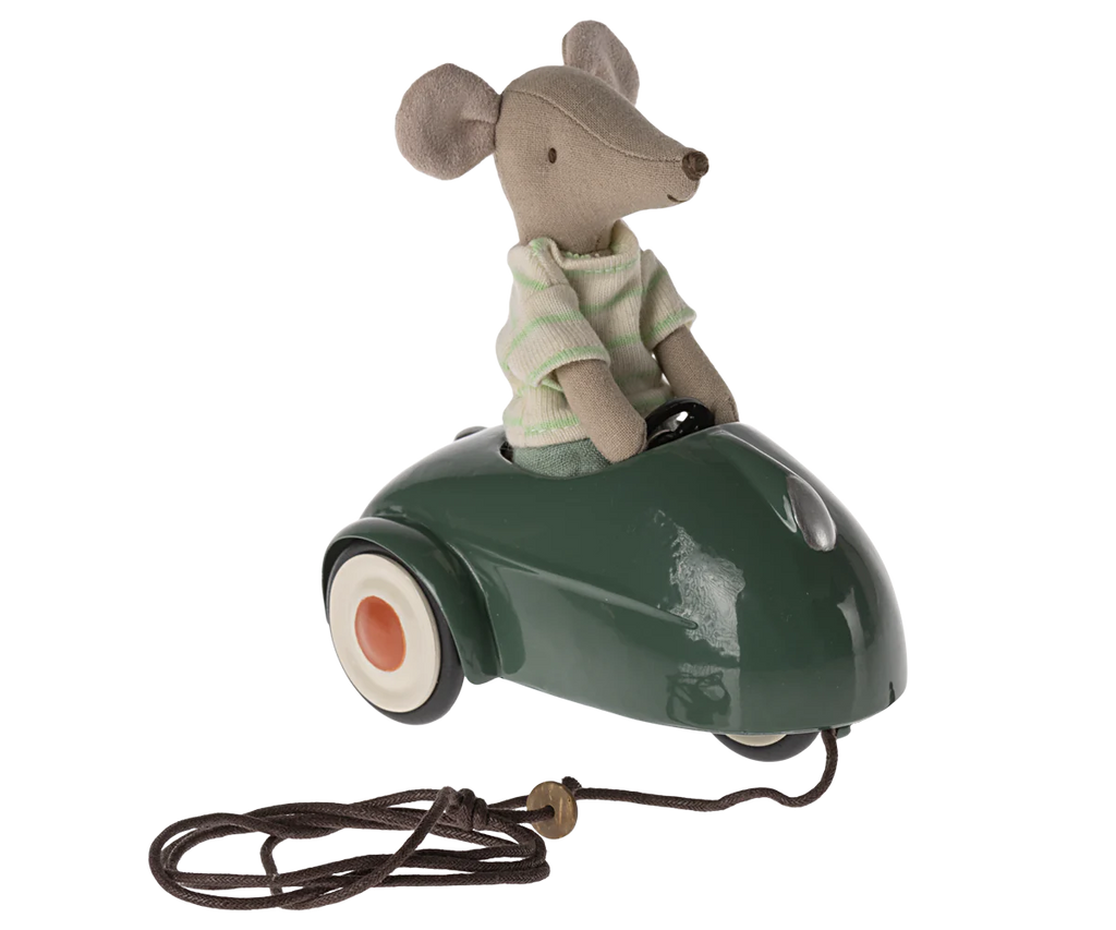 A Maileg Mouse Car - Dark Green sits in a green vintage-style metal car with a pull-string attached in front, against a striped background.