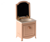 A small model of a vanity sink with a mirror. The Maileg Sink Dresser With Mirror, Mouse features a white countertop, gold faucet, and cabinet door. The mirror, framed in pink, is removable for easy cleaning. Perfect for adding a touch of elegance to your Maileg mouse castle's royal bathroom with its vintage design.