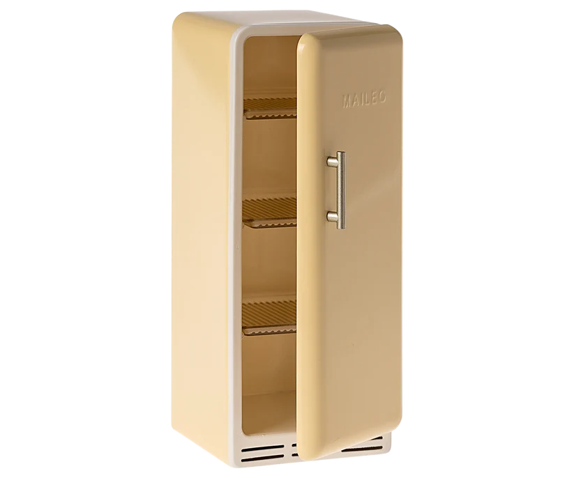 A miniature, vintage-style yellow fridge perfect for a Maileg dollhouse, with its door slightly open to reveal three empty wire shelves inside. The fridge has a simple, sleek design with the word "MAILEG" embossed near the top.