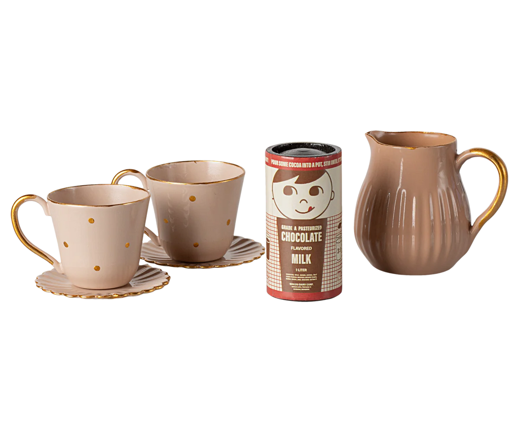 A Maileg Hot chocolate set, Mini is accompanied by two polka-dotted teacups with saucers and a matching creamer pitcher, evoking the cozy gatherings of the Teddy family. The arrangement showcases a warm color palette with gold accents on the cup handles.