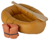 A small, fabric inflatable boat with wooden paddles and an orange life jacket attached is perfect for a pretend water adventure. The Maileg Rubber Boat is orange with a textured surface, and two rectangular wooden paddles rest on top. The bundled orange life jacket, secured by a black strap, sits next to the boat.