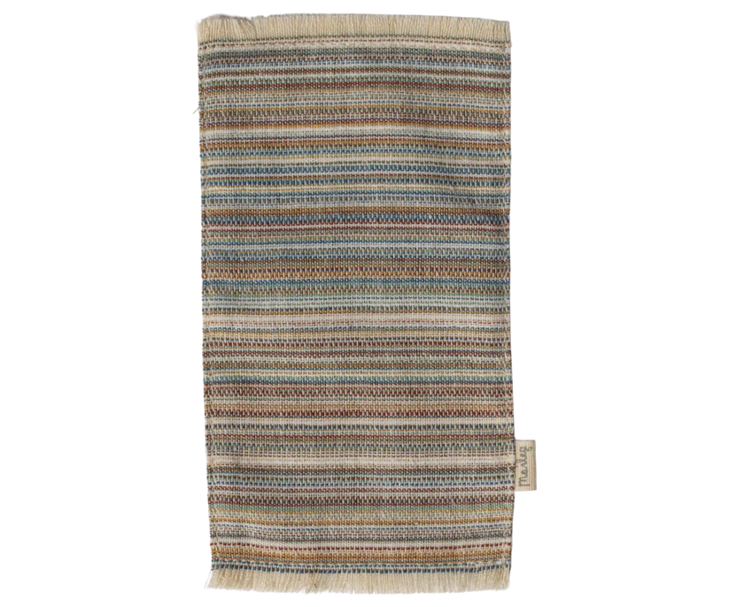 The Maileg Striped Rug, Large, is a rectangular woven cotton rug featuring horizontal stripes in earthy tones like brown, blue, and beige. Its fringe details along the edges make it an ideal door mat.