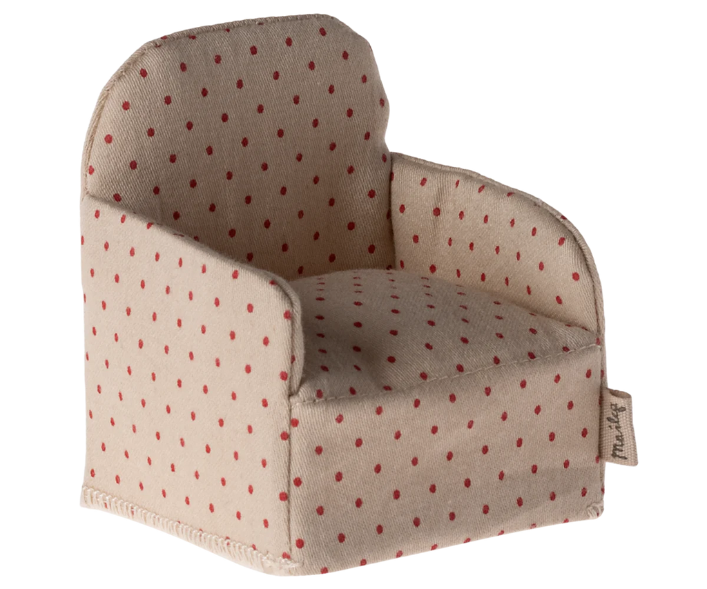 Introducing the Maileg Chair, Mouse - Dot: a delightful, small beige fabric armchair adorned with red polka dots. This charming piece features a rounded back and includes a little tag on the side, capturing the whimsical essence of a gingerbread house. It's an ideal addition to your Maileg chair collection and perfect for small Maileg friends to relax in style.