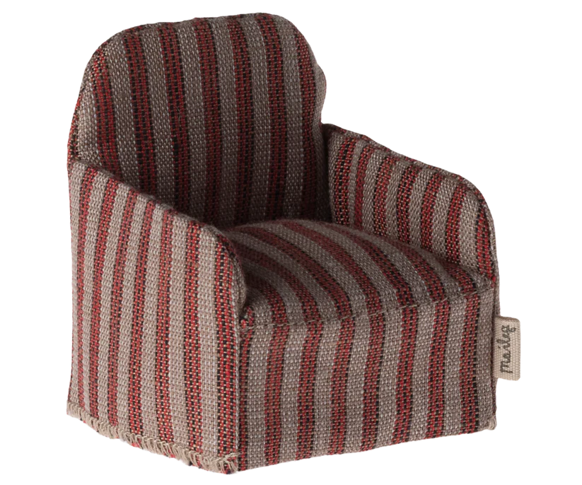 The Maileg Chair, Mouse - Striped is a cozy, fabric-wrapped seat with red and gray vertical stripes, ideal for your Maileg friends. It has boxy armrests, a straight back with a textured look, and a tag on one side, making it perfect to place beside your Gingerbread House décor.