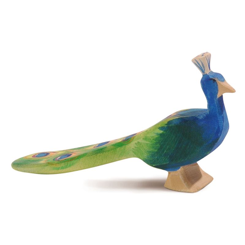 The Ostheimer Peacock, a wooden, hand-painted figurine by the Ostheimer brand, features a vibrant blue body and a green tail adorned with eye-like patterns in blue and yellow. With a small crest on its head, this handcrafted wooden toy is simple yet detailed, making it perfect for imaginative play while capturing the elegant shape of a peacock.