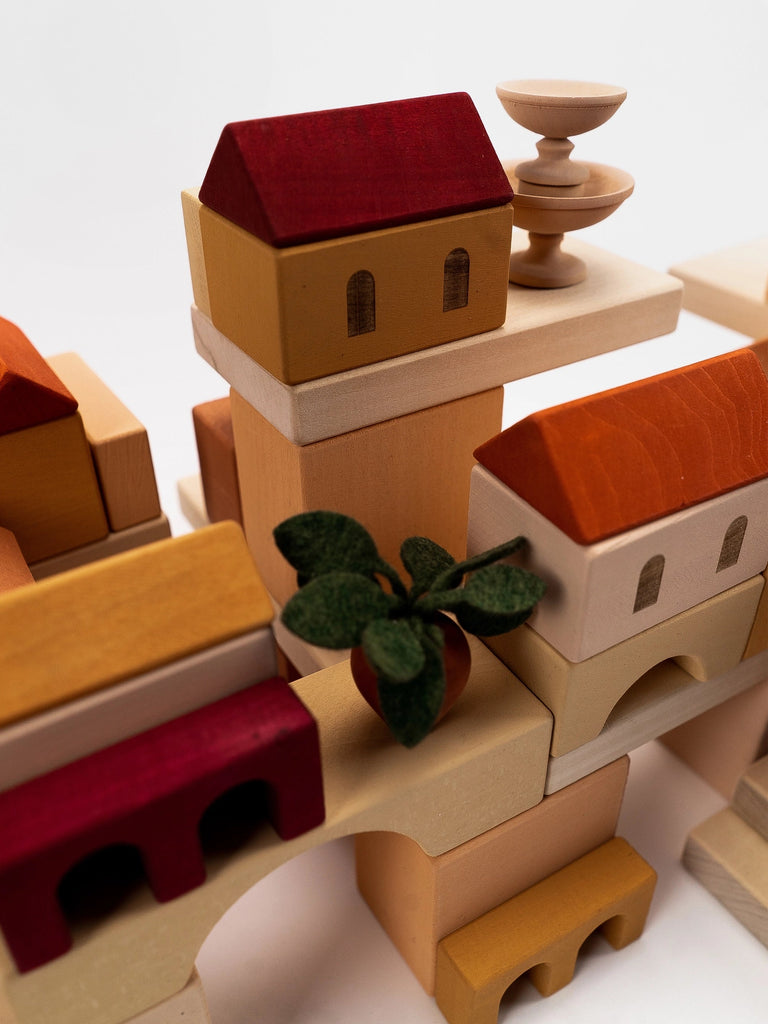 A close-up of a creatively assembled structure made from Sabo Concept Italian Courtyard Blocks, featuring a small plant with red berries at the center.