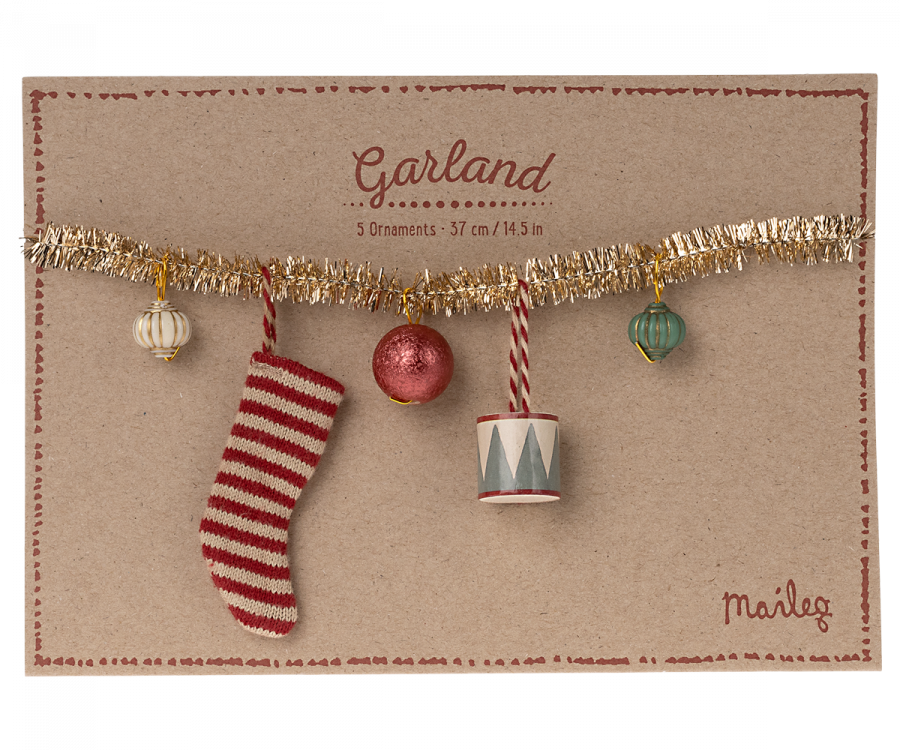 The Christmas garland, Small - Gold is displayed on a brown card, highlighting festive decorations. It features a decorative garland adorned with five ornaments: a striped stocking, a red bauble, a cylindrical piece, and two spherical ornaments in white and green. The card reads "Garland" along with its measurements in centimeters and inches.