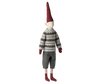 A Maileg Christmas Mega Pixy (Size 6) with a long red pointy hat, wearing an exclusive materials grey sweater with a white and black pattern, grey shorts, and striped socks, isolated on a black background.