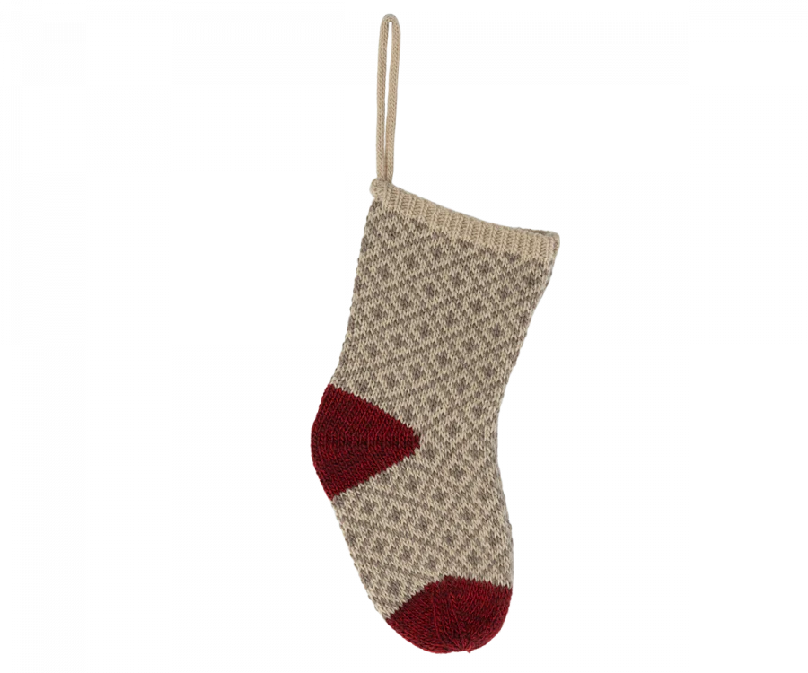 A decorative Maileg Christmas Stocking in soft grey with a textured pattern hangs against a black background. The heel and toe are dark red, enhancing the festive appearance. A convenient loop at the top makes it ideal for holding small gifts, adding charm to your holiday decor.