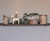 The shelf features a mug, a reindeer decoration, a white horse figurine with a lit candle, pine branches, and two tins from the Maileg Metal Box 2 Piece Set - Winter Wonderland collection. This festive display combines natural and Scandinavian-inspired elements for a cozy atmosphere.