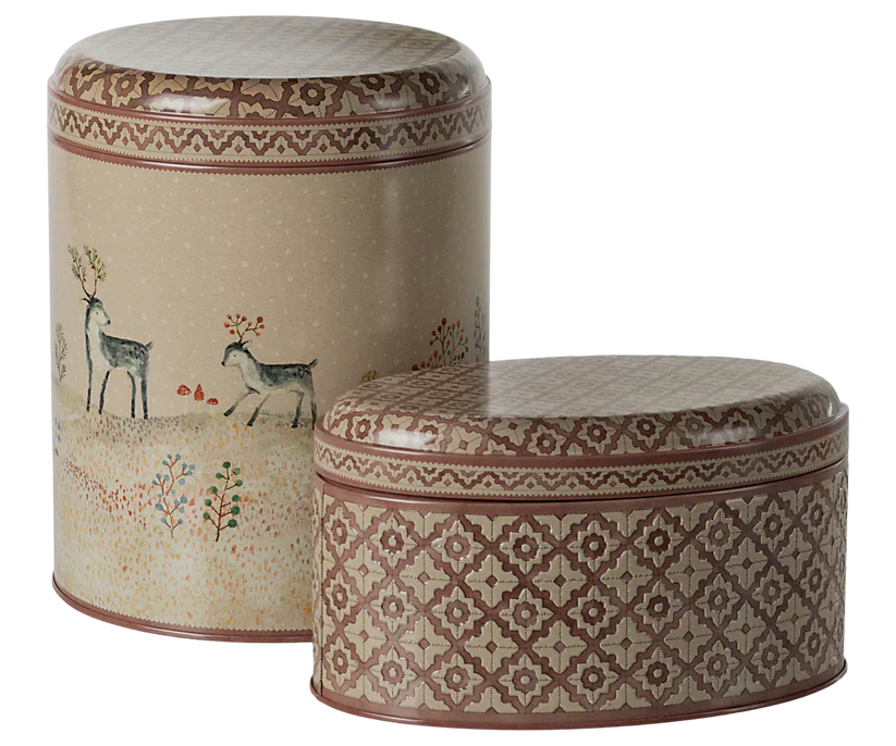 As part of the Maileg Metal Box, 2 Piece Set - Winter Wonderland, these decorative tins feature intricate designs. The taller tin is adorned with deer, trees, and snowflakes on a cream background, while the smaller tin displays a geometric mosaic pattern in earthy tones—perfect for storing Christmas sweets.