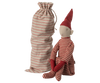 The Maileg Long Legged Pixy, Large, dressed in red and white striped clothing with a pointy hat, sits beside its matching striped drawstring bag. This whimsical creature with pointed ears adds a touch of magic to your decor.