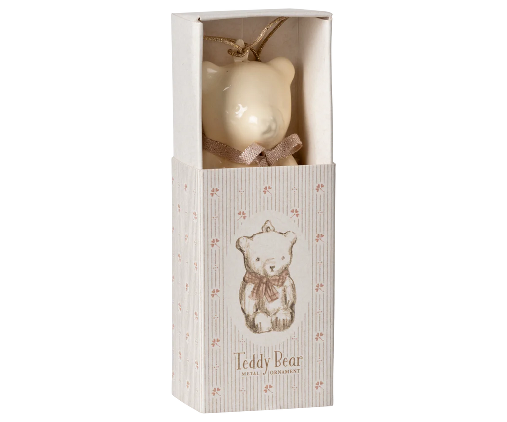 Product Description: The Maileg Metal Ornament, Teddy Bear in Off White/Rose is beautifully presented in a decorative box adorned with an illustration of a teddy bear and the phrase "Teddy Bear Metal Ornament." Featuring charming handpainted details, this cream-colored ornament comes with a small ribbon and is securely packaged.