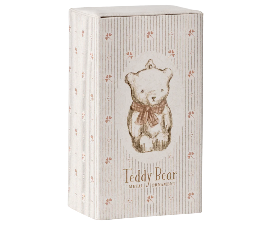 An off white and rose striped box showcasing a vintage-style teddy bear illustration with a bow tie, featuring handpainted details. The text reads "Maileg Metal Ornament, Teddy Bear - Off White/Rose." The box is adorned with a delicate pattern of small floral designs, characteristic of Maileg ornaments.