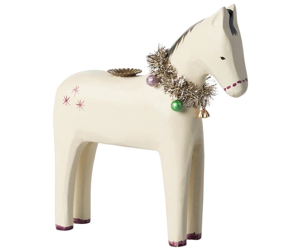 The Maileg Wooden Horse Candle Holder captures a cozy Christmas ambiance as it features a festive garland of metallic tinsel, purple and green baubles, and a small gold bell. This white wooden horse showcases simplistic painted details with subtle star motifs on its side.