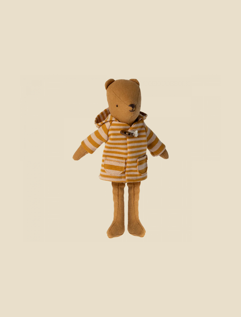 A plush teddy bear donning an ocher-striped orange and yellow hoodie with a front pocket stands upright against a beige background, radiating a cozy charm reminiscent of the Maileg Extra Clothing: Coat for Teddy Mum.