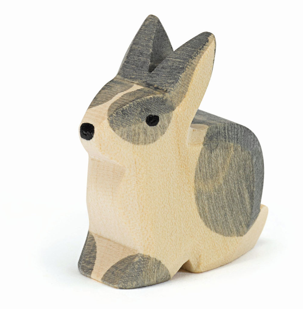 The Ostheimer Black & White Rabbit - Sitting is a small, handcrafted wooden figurine, showcasing a smooth finish with natural wood grain visible. Painted in shades of black and white, it achieves a rustic and minimalist design. Its upright ears and seated position inspire imaginative play.