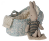 A Maileg Rabbit in Carry Cot, Micro - Blue sitting inside a floral-patterned miniature carry cot with a knitted blanket. The setting is isolated on a white background.