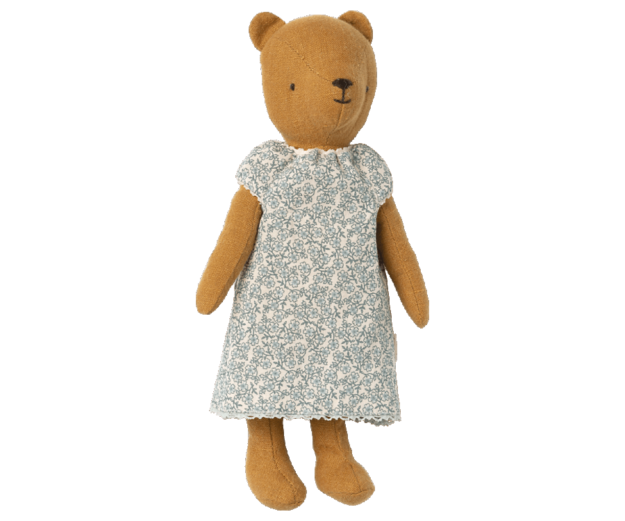 A brown plush bear, fondly known as Teddy Mum, is dressed in a green outfit with a white floral pattern. The bear's simple stitched face has a small nose and eyes, and its round ears add to its charm. The Maileg Extra Clothing: Nightgown for Teddy Mum, which can be purchased separately, features white lace trim on the hem and sleeves. Teddy Mum stands upright against a white background.