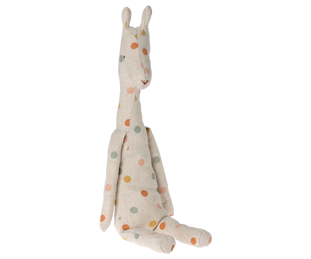 A beige Maileg Medium Giraffe plush made from recycled polyester rests against a surface. Its long neck, ears, and limbs are elegantly adorned with orange, green, and blue polka dots, making it the perfect safari companion with its charming and playful design.