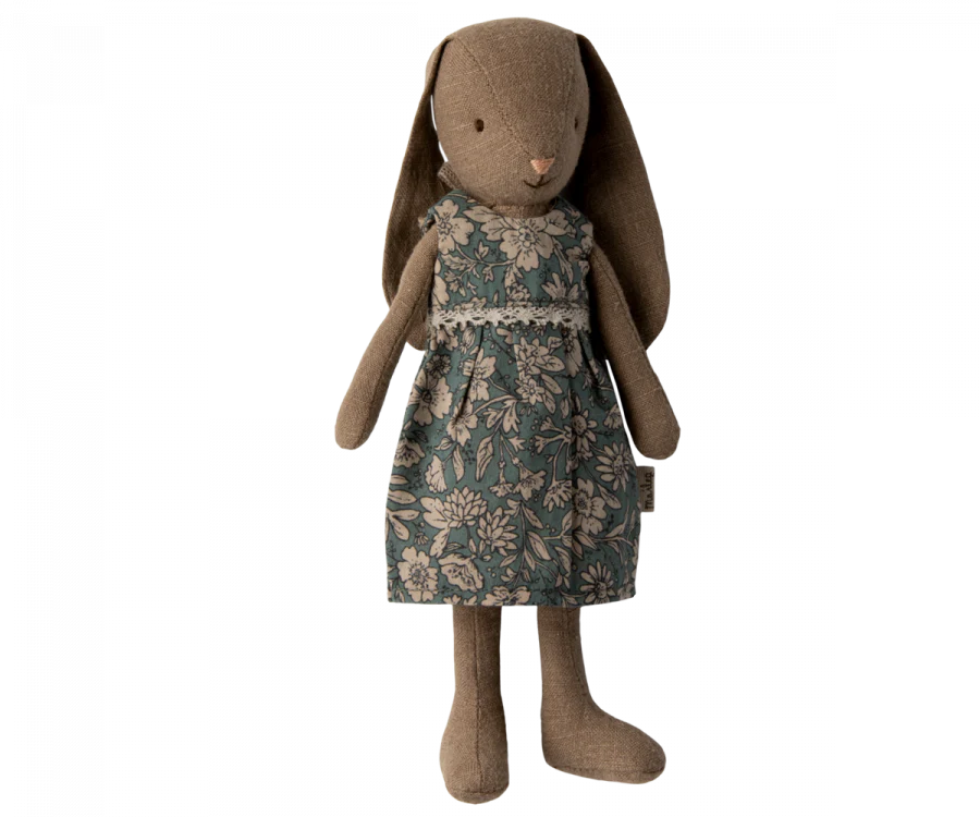 A stuffed brown bunny, Maileg Bunny, Size 1, Brown - Blossom Dress, wearing a floral-patterned dress in shades of grey, beige, and blue. The Maileg fabric adds a touch of elegance to this cuddly toy from the FW23 collection. Standing upright with large floppy ears hanging down its sides, it's perfect for any dollhouse or nursery.