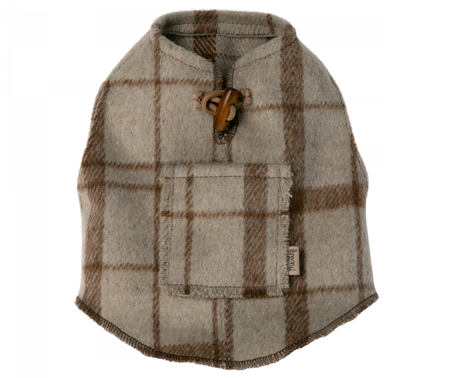 A gray and brown plaid wool Maileg Puppy Poncho with a leather toggle closure at the neck and a small rectangular pocket on the back. Featuring a convenient small tail hole, the fabric tag on the side reads "Found." The poncho is laid flat on a white background.