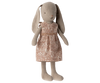 A Maileg Bunny, Size 1 - Classic Flower Dress stands upright, wearing a pink dress adorned with a white floral pattern. Made from recycled polyester, the bunny has long ears, a simple stitched face, and a gentle, neutral color.