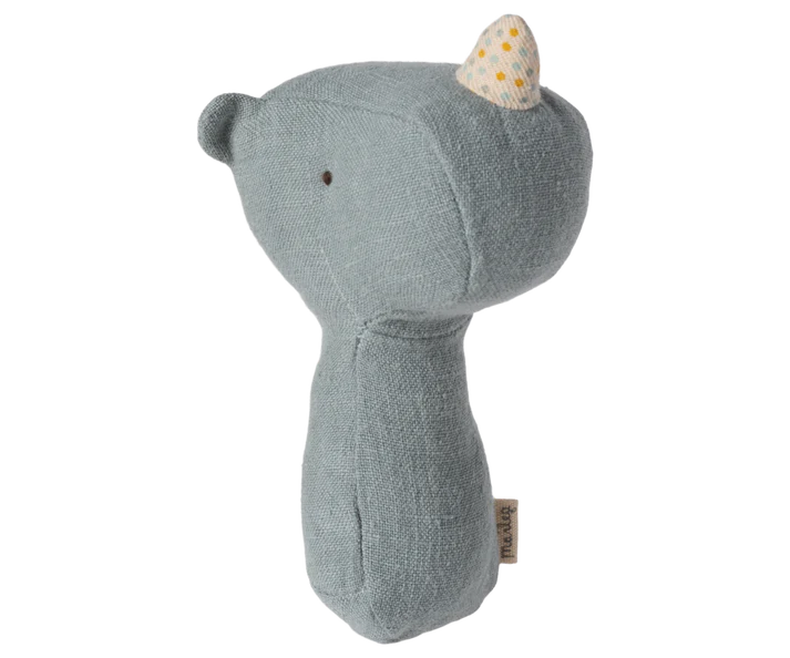 The Maileg Lullaby Friend Rattles, Rhino in Dusty Blue is a soft, plush toy shaped like a rhinoceros. Crafted from soft fabrics, it features a blue-grey body and a small white horn adorned with yellow dots. The minimalistic design includes simple stitched eyes and no other facial features. Perfect for adding to a gift box, it also comes with a small tag attached to its side.