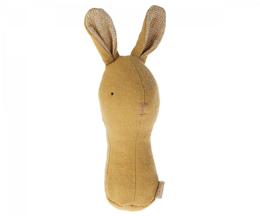 A Maileg Lullaby Friend Rattles, Bunny - Dusty Yellow shaped like a bunny with long ears, simple stitched eyes, and a small stitched nose. The ears have a checked pattern on the inner side. This minimalist design includes a gentle baby rattle and comes in an elegant gift box, perfect for any occasion.