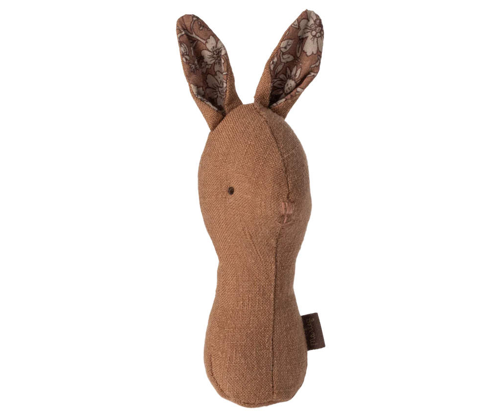 The Maileg Lullaby Friend Rattles, Bunny Rattle - Chocolate features a handmade, fabric bunny toy with long ears, crafted from soft, brown textured cloth and lined with floral patterned fabric. This simple, minimalist design includes small stitched eyes and a nose. Packaged in an elegant gift box, it doubles as a charming baby rattle for little hands.